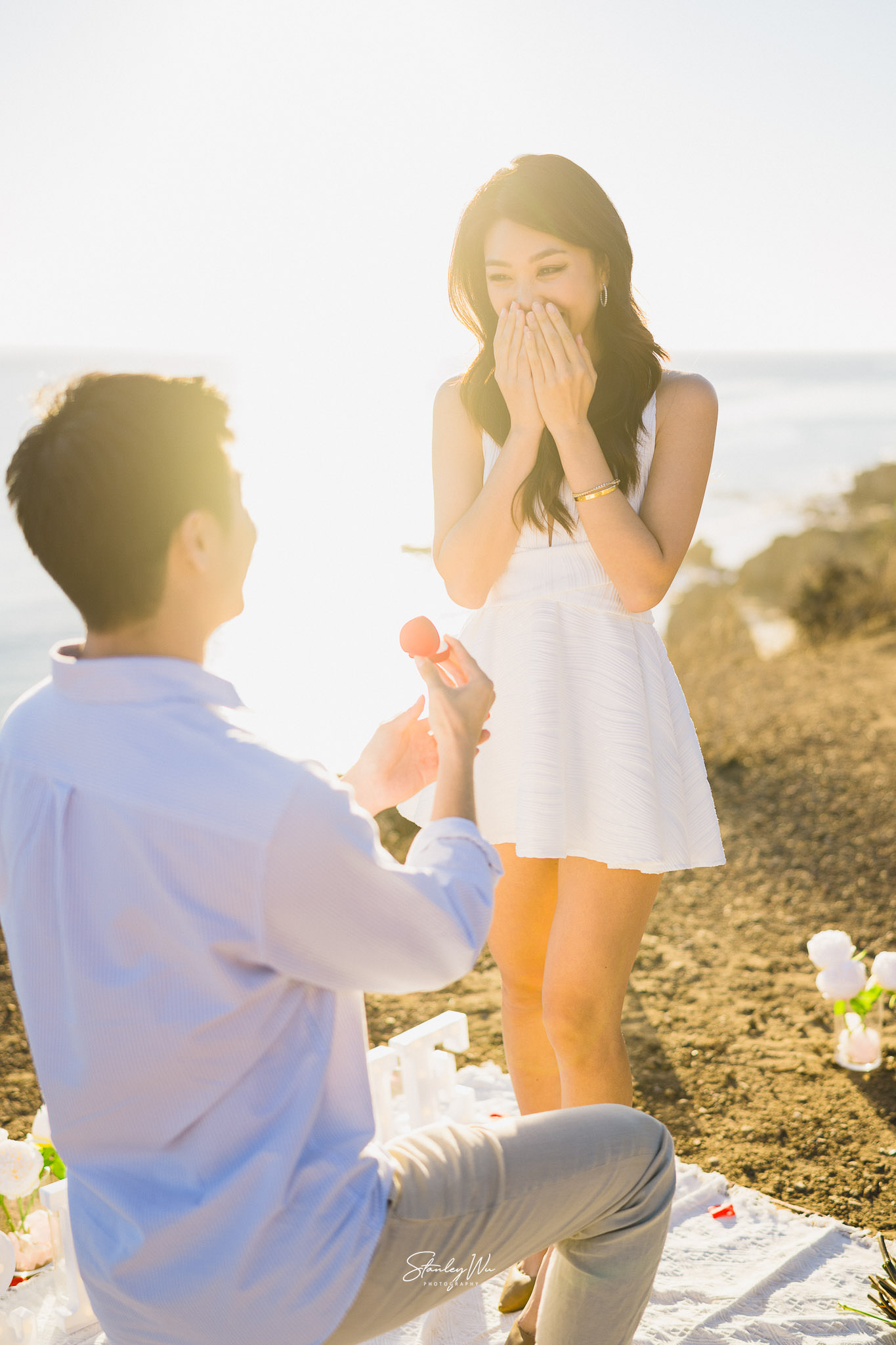 Man proposing to his fiance atop the cliffs in Malibu, fiance is pleasantly surprised